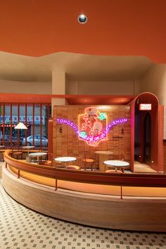 the inside of a restaurant with tables and stools in front of an orange wall