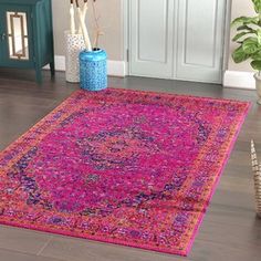 a pink area rug in front of a blue vase with flowers on the floor next to it