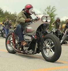 a man riding on the back of a motorcycle down a street next to other motorcyclists