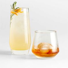 two glasses filled with drinks next to each other on a white surface, one has an orange flower in it