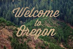 the words welcome to oregon written in gold on a mountain slope with trees behind it