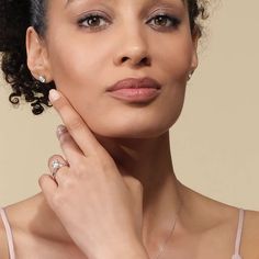 a woman with her hand on her chin, wearing a diamond ring and pink dress