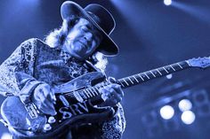 a man with a cowboy hat playing an electric guitar