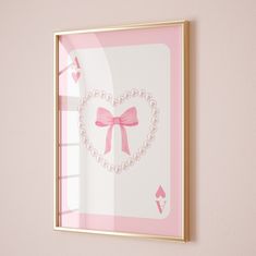 a pink and gold framed card with a bow on it's side, in front of a wall