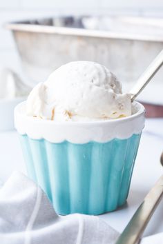 a blue cup with ice cream in it on a white table next to silverware