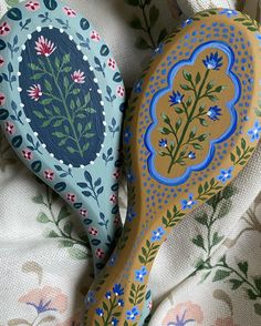 two decorative wooden paddles sitting on top of a floral print cloth covered tablecloth