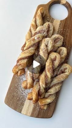 a wooden cutting board topped with lots of doughnuts and powdered sugar on top