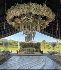 an outdoor wedding venue set up with flowers and chandeliers hanging from the ceiling