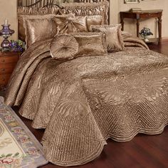 a bed with gold comforter and pillows on it in a room next to a rug