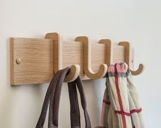 two purses are hanging on a coat rack with three coats attached to the hooks