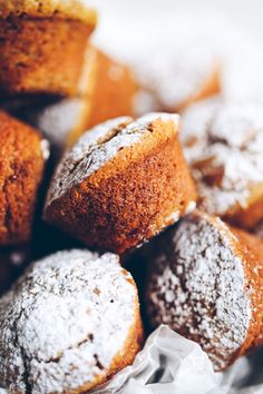 powdered sugar covered muffins sitting on top of each other in a pile