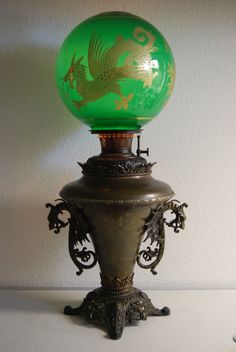 a green glass ball sitting on top of a metal stand next to a white wall