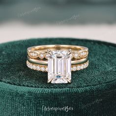 an emerald colored diamond engagement ring set on top of a green velvet box