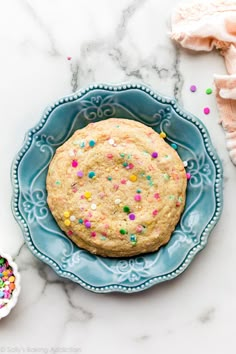 a cookie with sprinkles is on a blue plate next to other cookies