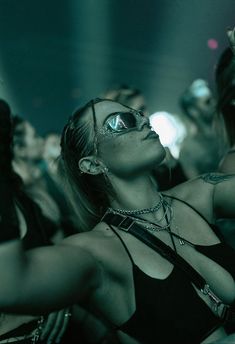 a woman with her eyes closed in the crowd at a music concert, wearing sunglasses