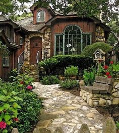 a stone path leading to a house with lots of plants and flowers in the front yard