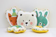 three pillows and two stuffed animals on a white surface