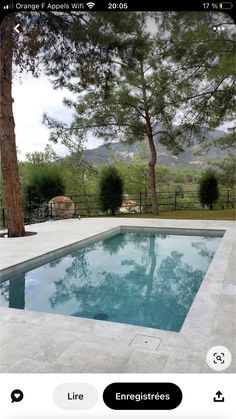 an empty pool in the middle of a yard with trees and mountains in the background