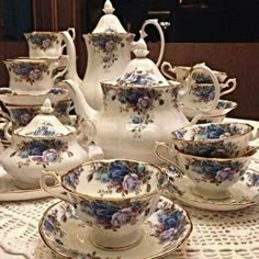 a table topped with lots of white and blue dishes covered in floral designs on top of a doily