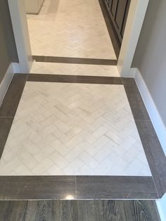 an empty hallway with white and gray tile on the floor