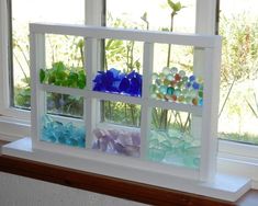 there are many different colored glass flowers in the window