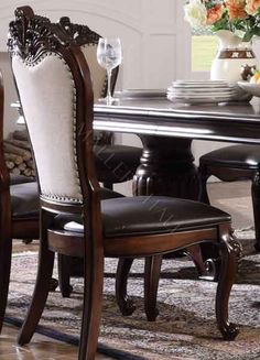 a dining room table with chairs and a vase full of flowers on the top shelf