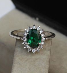 a ring with a green stone surrounded by white diamonds