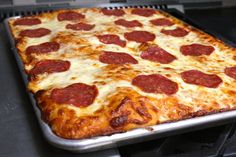 a large pepperoni pizza sitting on top of a stove