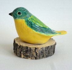 a yellow and green bird sitting on top of a piece of wood