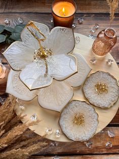 a white plate topped with flowers next to a candle and some glass candlesticks