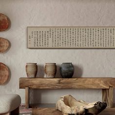 a wooden bench sitting in front of a wall with vases on top of it