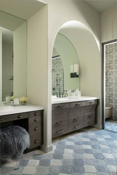 a large bathroom with two sinks, mirrors and a bench in the middle of it