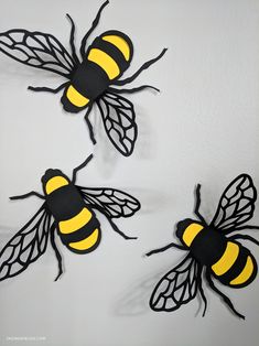 three black and yellow bees on a white wall