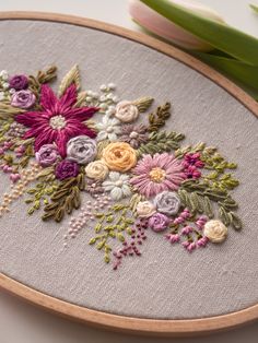 a close up of a embroidery on a hoop with flowers in it and tulips