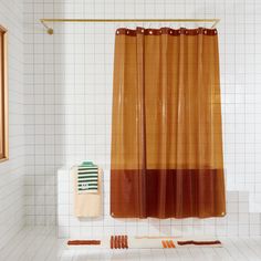 an orange and brown shower curtain next to a white tiled wall in a bathroom with tile flooring