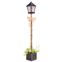 a lamp post with a bow on it and flowers in the planter next to it