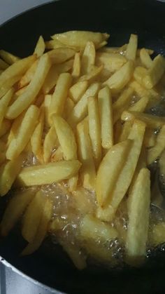 french fries being cooked in a frying pan