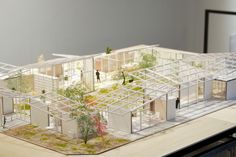 an architectural model of a house with trees and people in the yard, on top of a table