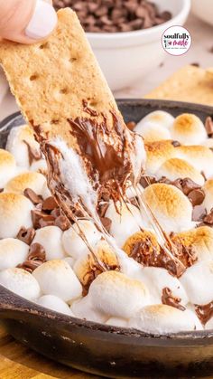 a person dipping marshmallows into a skillet with chocolate and graham crackers