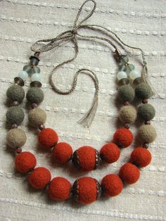 the necklace is made up of red and gray pompom beads with silver accents