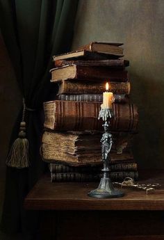 a stack of books with a candle on top of it sitting next to a key