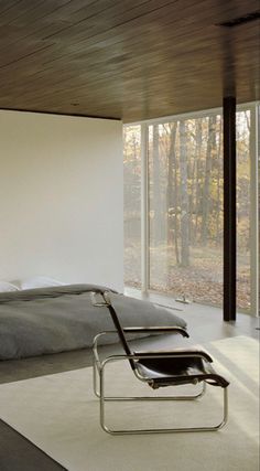 a bedroom with a large bed sitting next to a sliding glass wall that looks out onto the woods