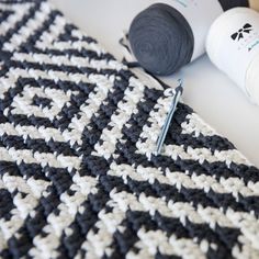 two crocheted items are laying on the table next to some yarn and scissors