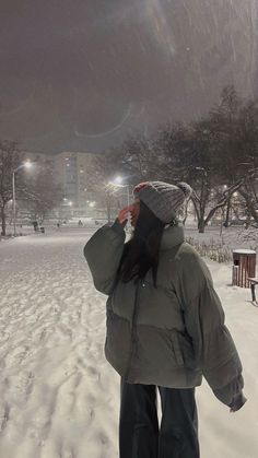 a person standing in the snow with their back to the camera, talking on a cell phone