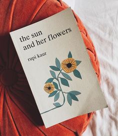 the sun and her flowers by rupi kaur is on top of an orange pillow