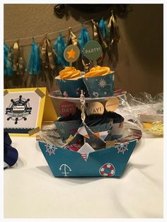 a table topped with lots of cupcakes on top of a cake stand next to other items