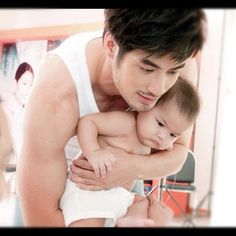 a man holding a baby in his arms while he looks at the reflection of him