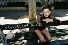 a woman sitting on top of a green bench