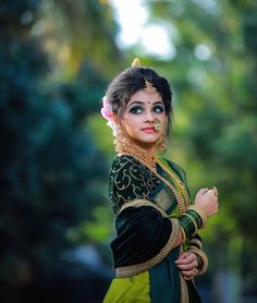 a woman dressed in green and gold poses for the camera with her arms folded out