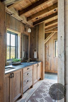 a bathroom with wooden walls and flooring has a large sink in front of the window